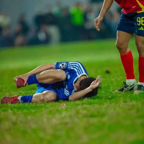 soccer player injured on grass holding his right foot